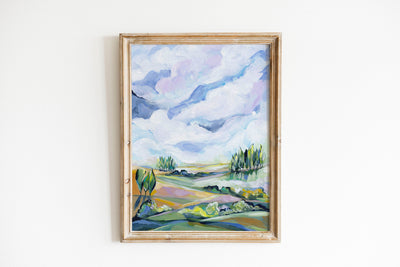 Framed painting of a landscape with trees and clouds on a white wall