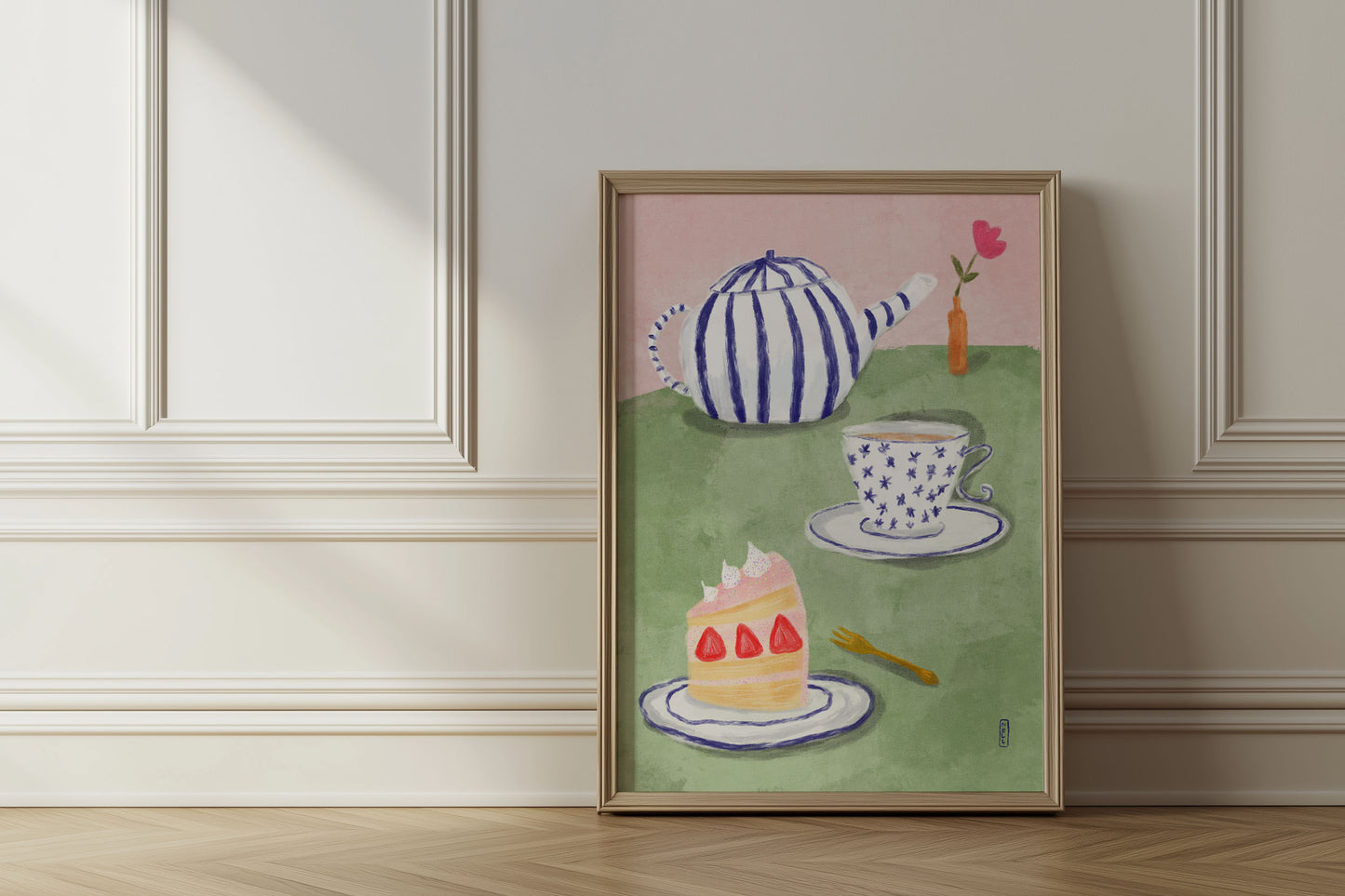 Framed artwork of a teapot, cake, and cup on a green background in a room with wooden flooring and white walls.