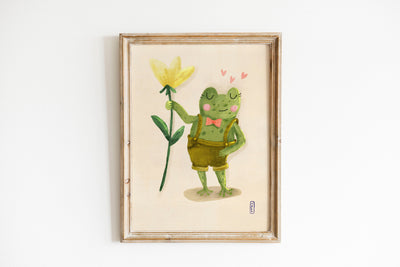 Framed artwork of a cartoon frog holding a yellow flower on a white background