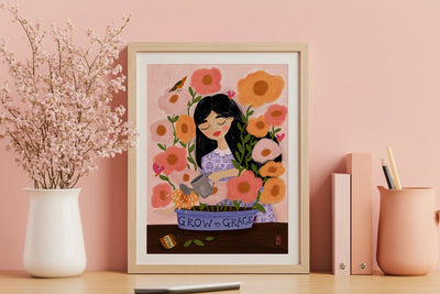 Framed artwork of a woman with flowers on a pink wall