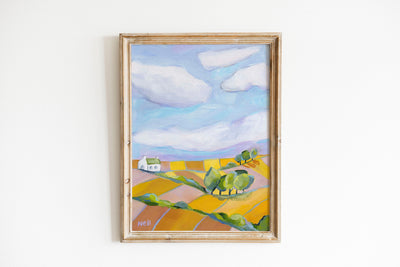 Framed painting of a landscape with a house and trees on a white wall
