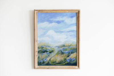 Framed painting of a landscape with blue flowers and a mountain on a white wall