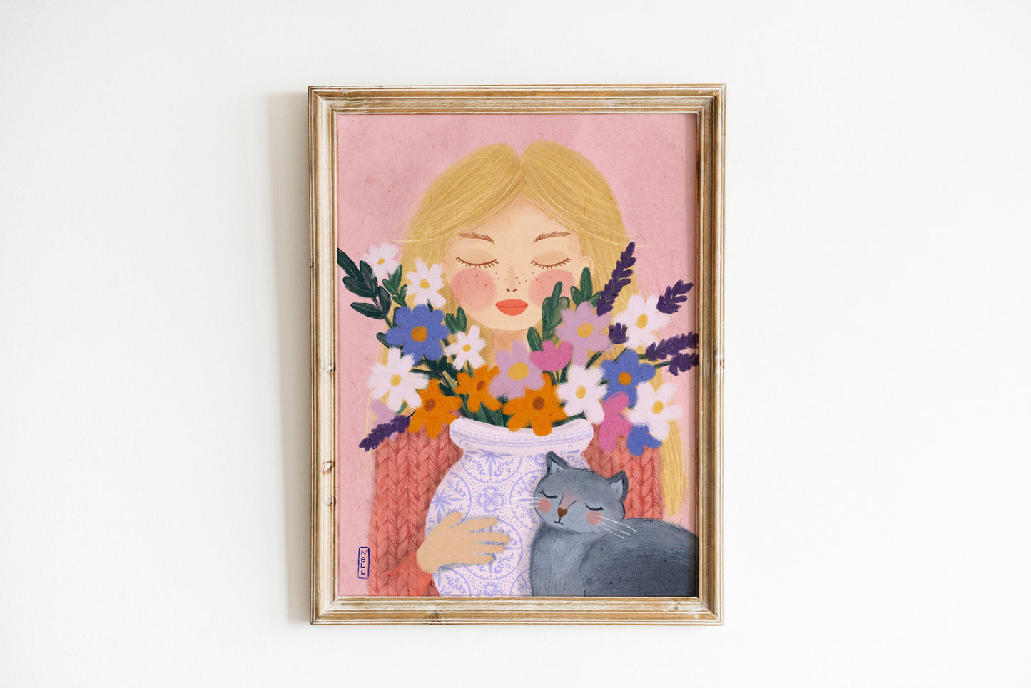 Framed artwork of a woman holding flowers with a cat on a pink background