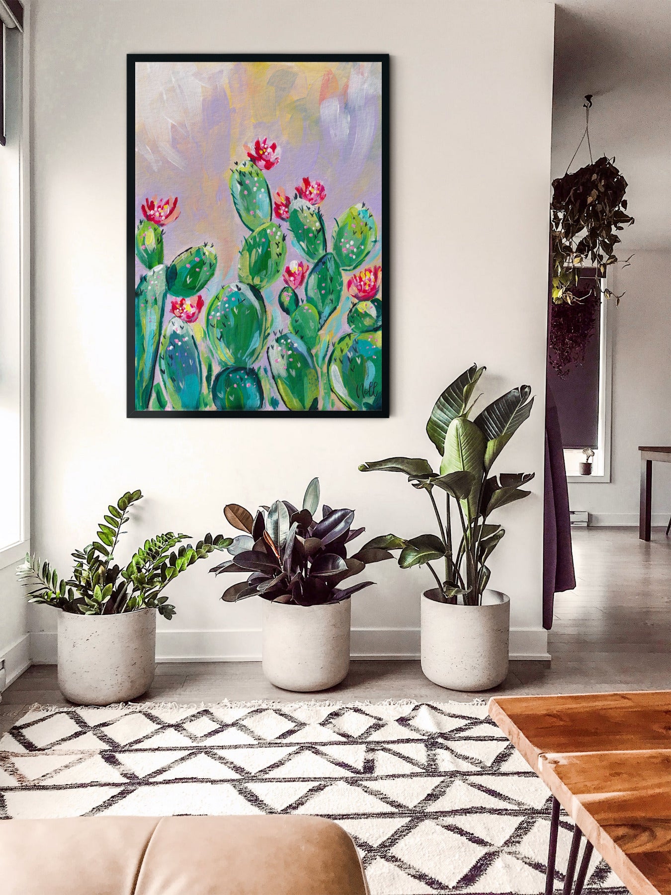 Living room with potted plants and a colorful painting of cacti on the wall.