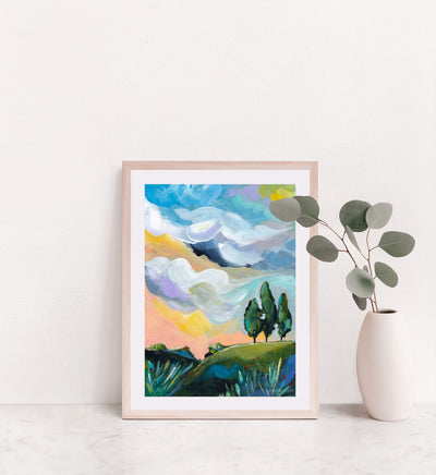 Framed abstract landscape painting on a white wall with a vase and plant.