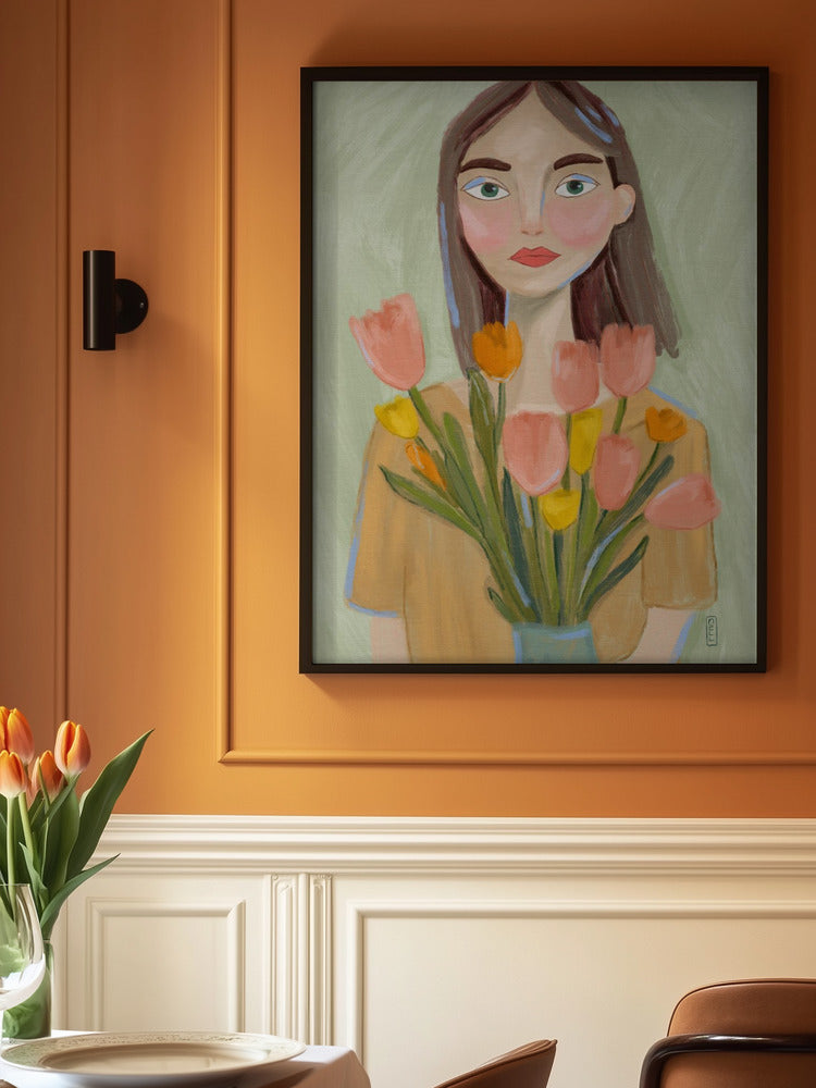 Framed painting of a woman holding flowers on an orange wall above a table with tulips.