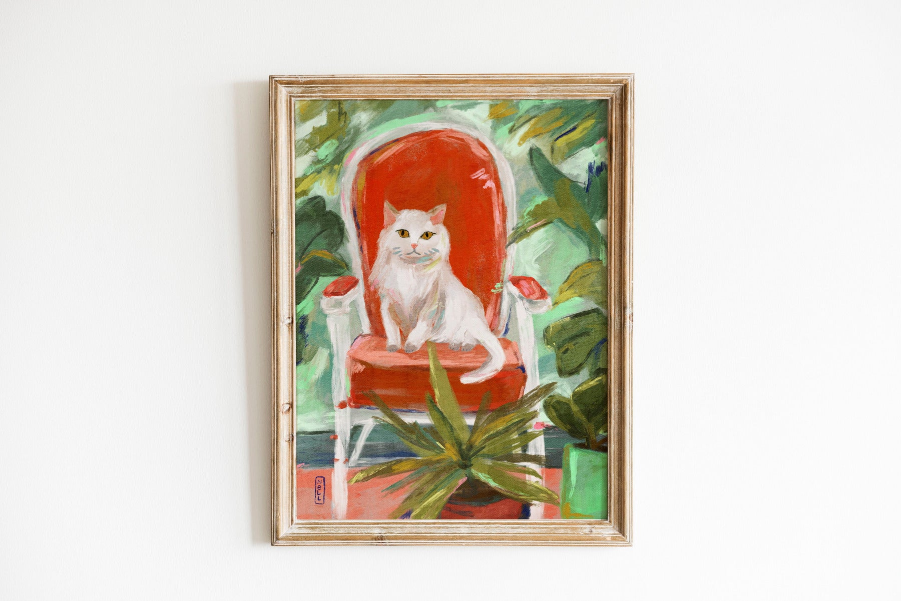 Framed artwork of a white cat on a red chair with green foliage.