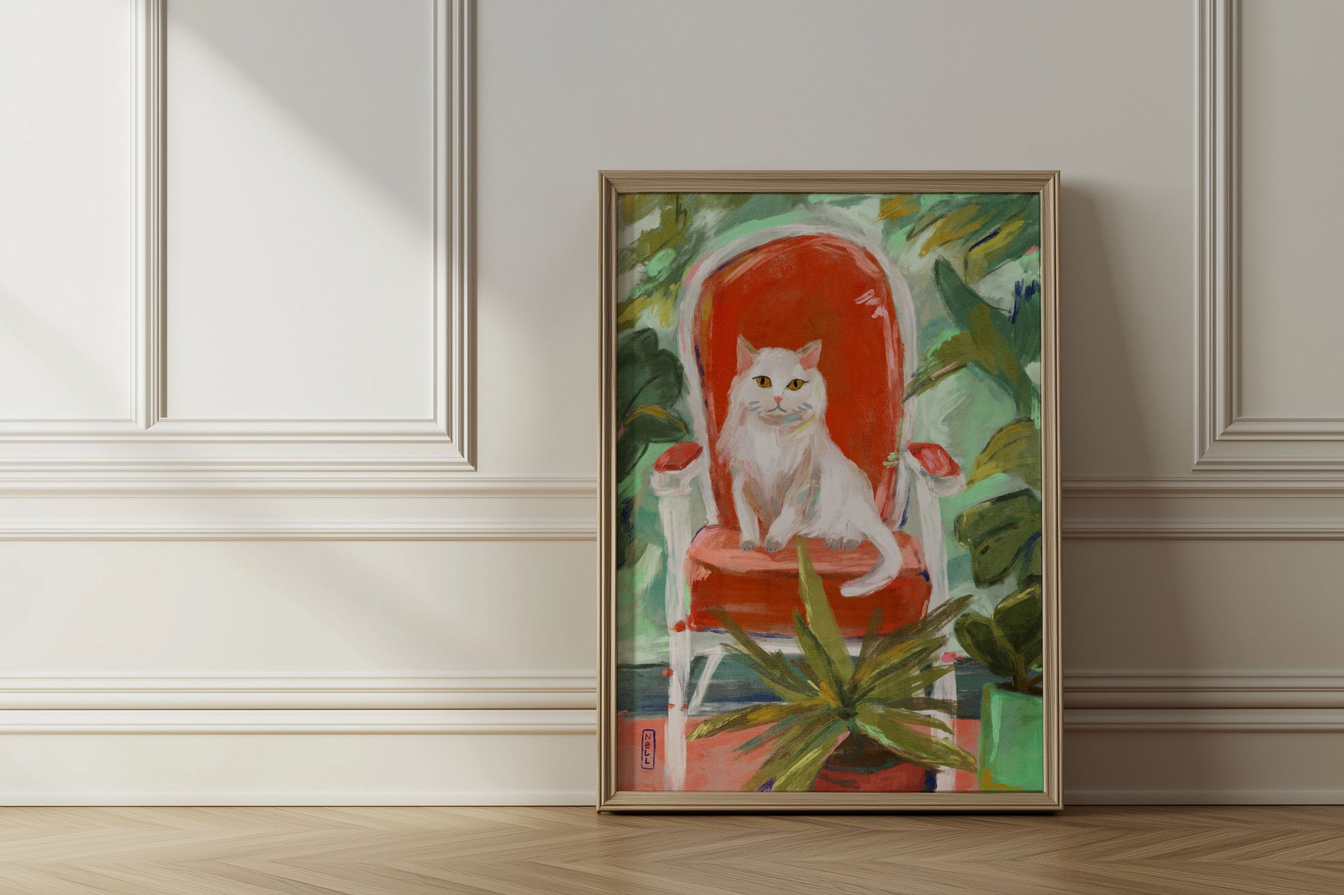 Framed painting of a white cat on a red chair with green foliage, displayed on a wall.