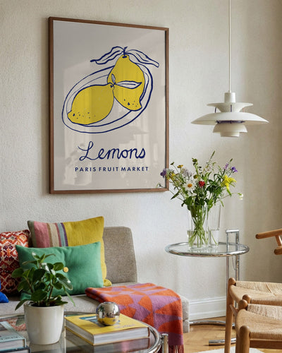 Living room with a 'Lemons' poster, colorful pillows, and a small table with flowers.