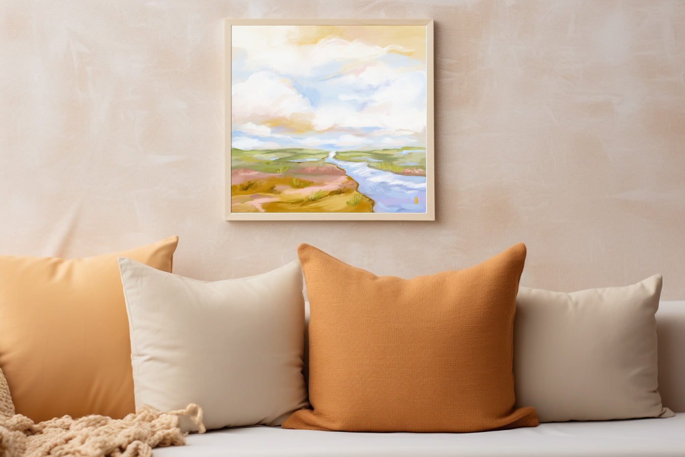 Framed landscape painting above a sofa with colorful cushions.