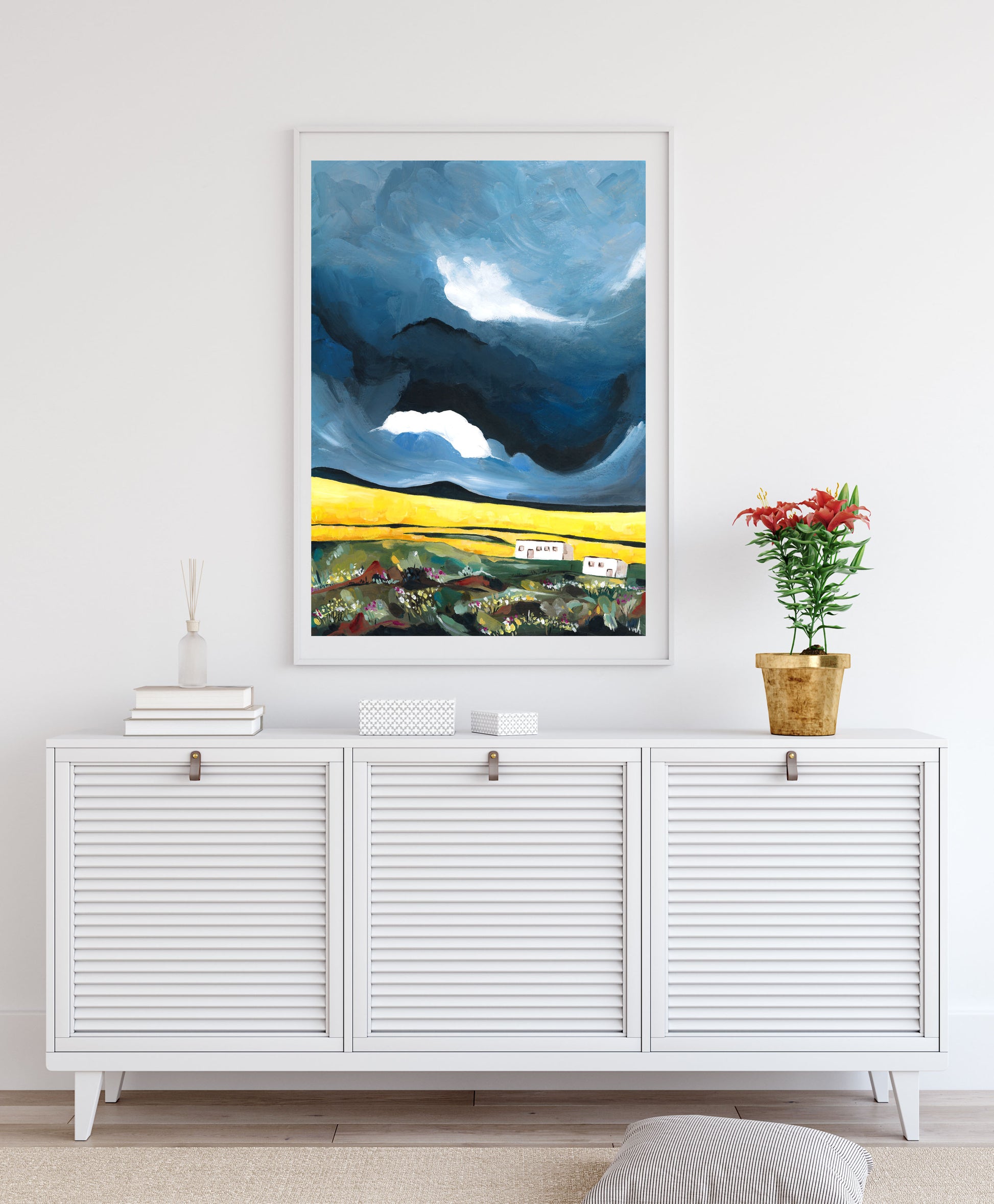 Framed abstract artwork on a wall above a white cabinet with decorative items.