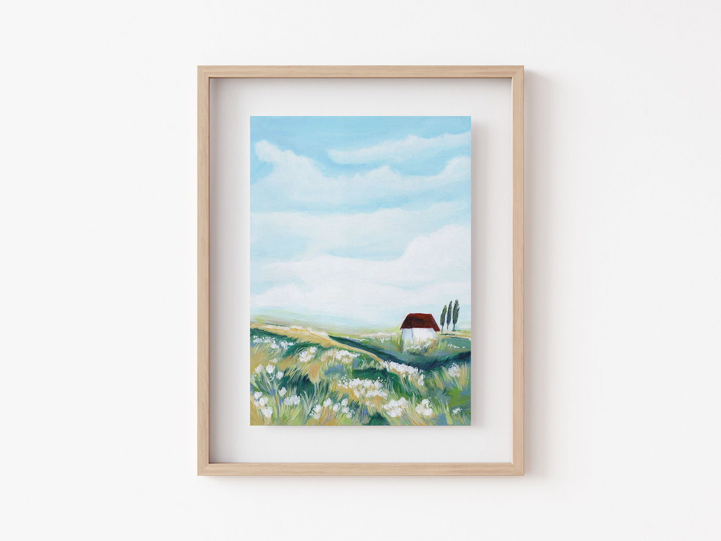 Framed painting of a landscape with a house on a white wall