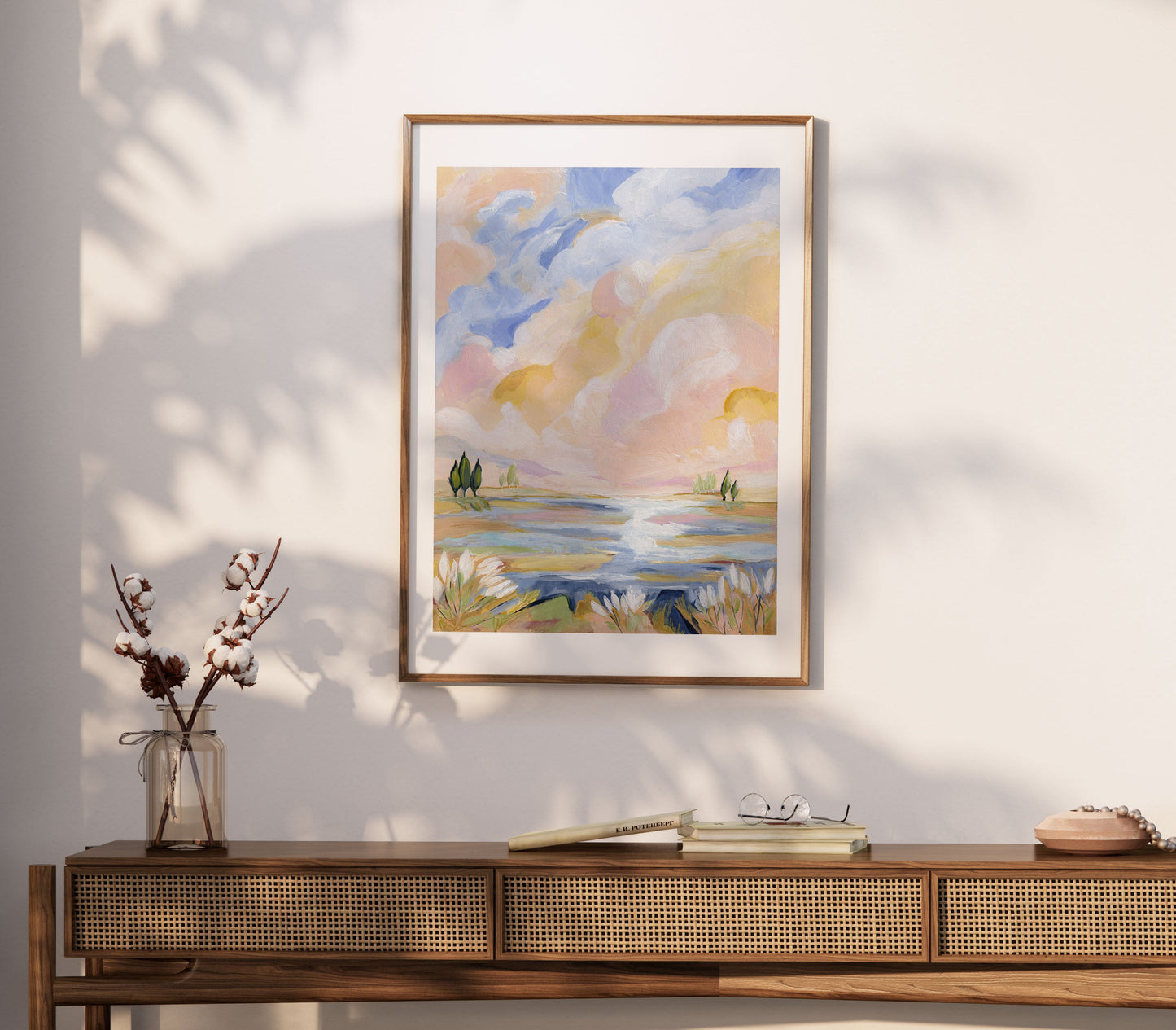 Framed landscape painting on a wall above a wooden console table.