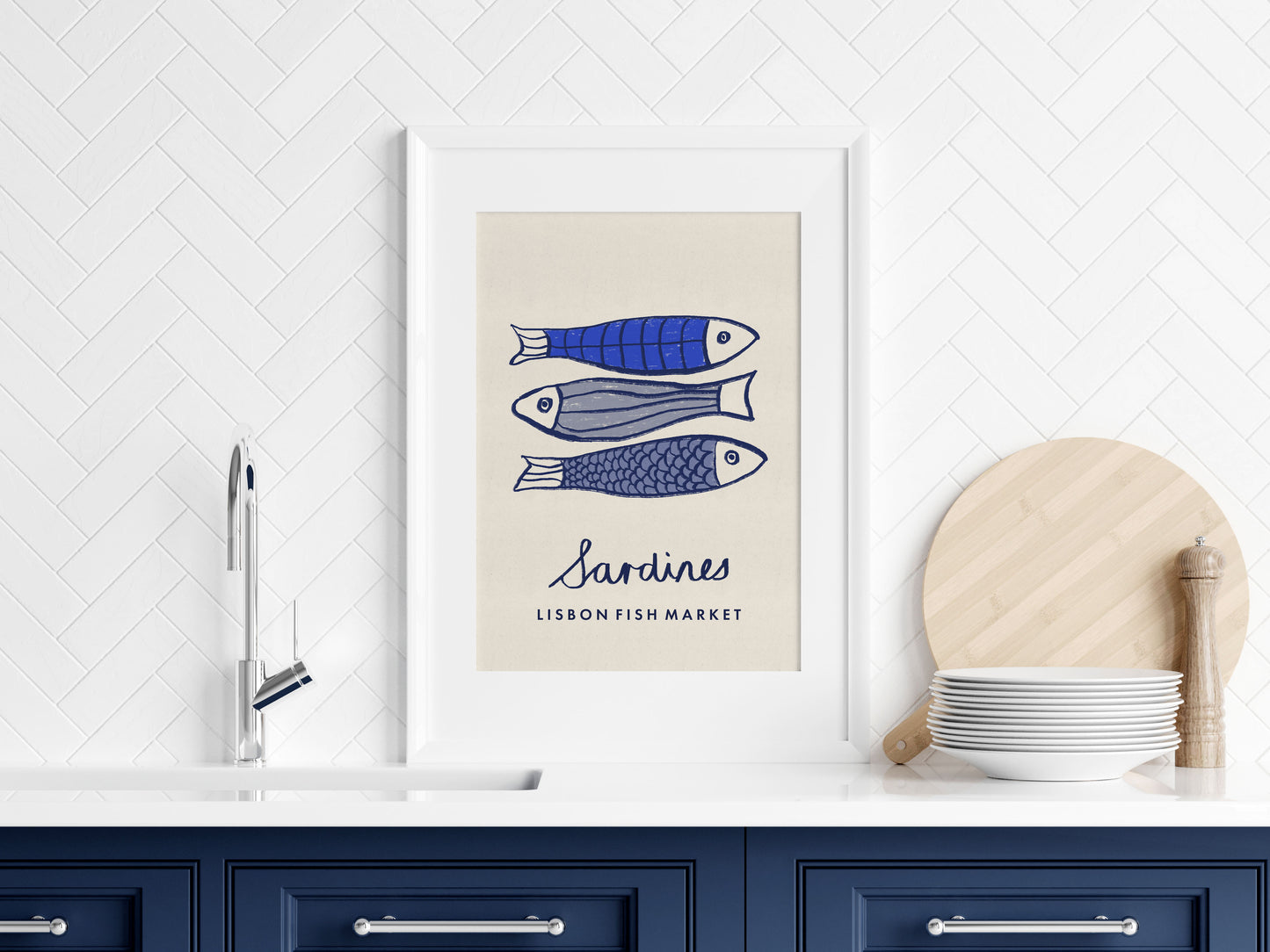 Framed artwork of sardines on a kitchen wall with blue cabinets and white tiles.