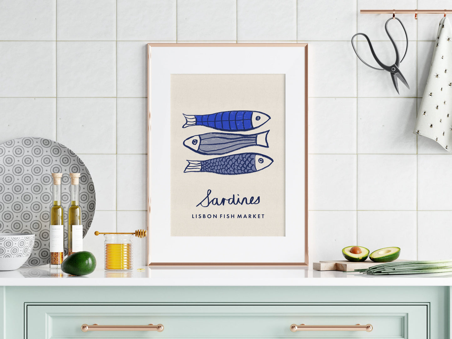 Framed artwork of sardines on a kitchen wall with decorative items.