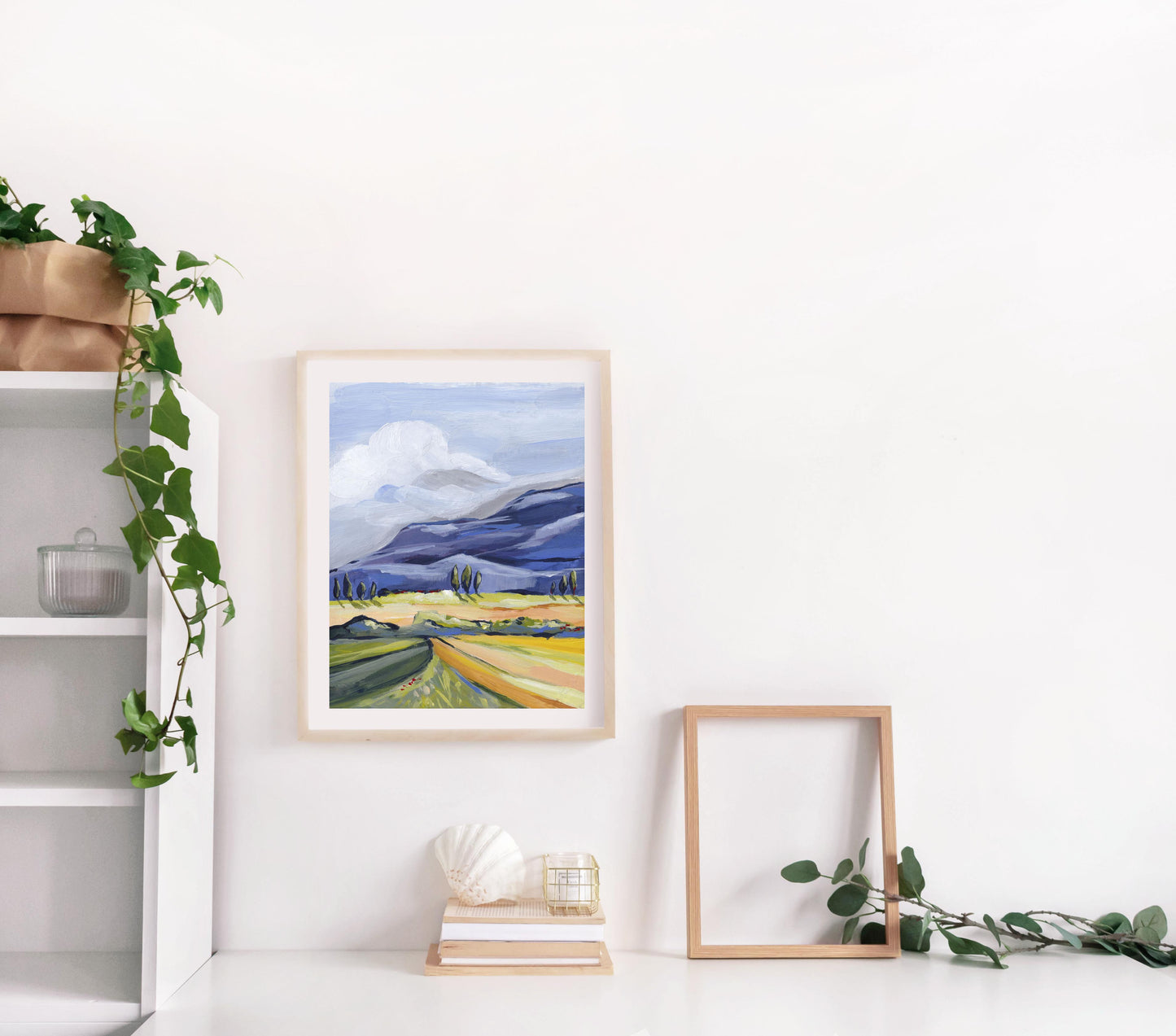 Framed landscape print on a white wall with decorative elements.