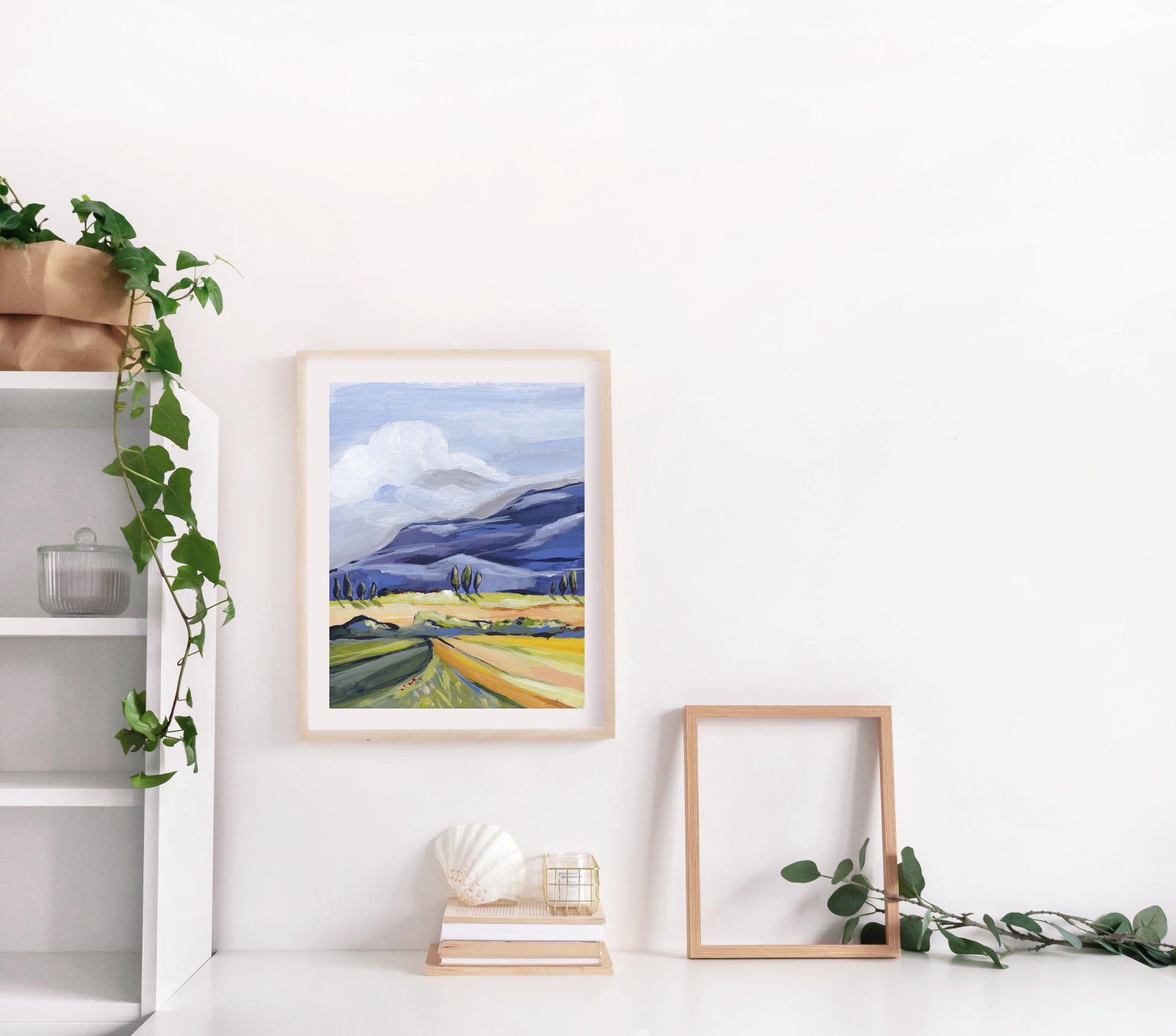 Framed landscape print on a white wall with decorative elements.